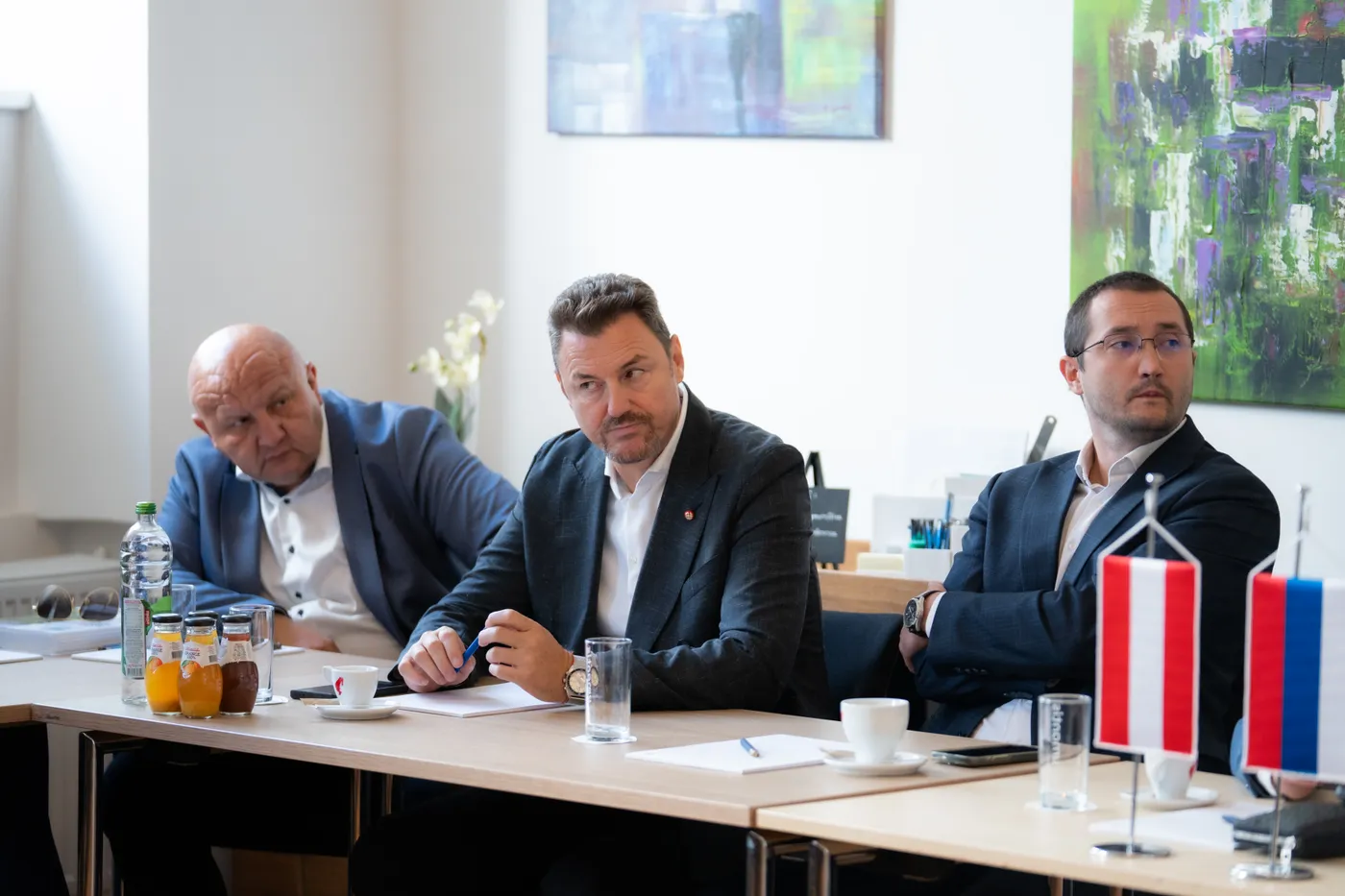 Drei Teilnehmer am Konferenztisch, davor die Tischfähnchen