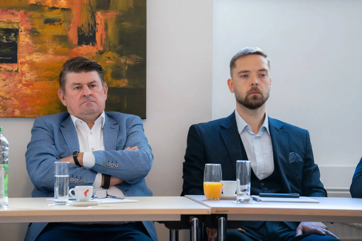 Zwei Teilnehmer während des Vortrags, vor ihnen Gläser und Unterlagen
